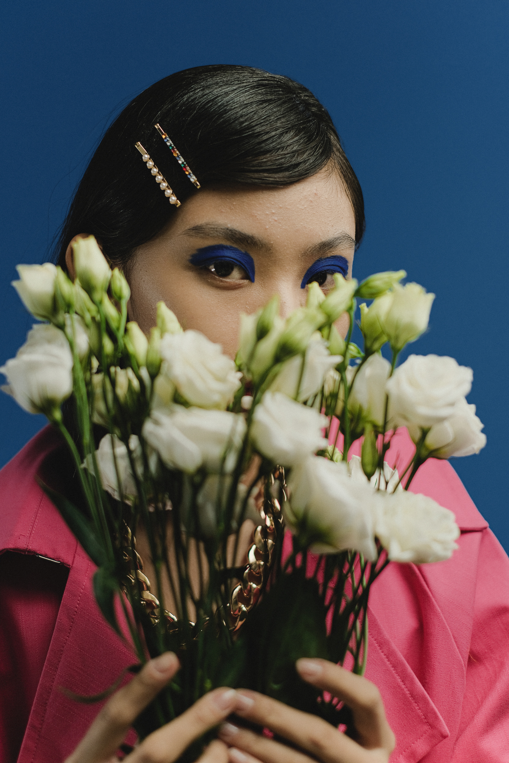  A Woman in a Pink Coat Holding White Roses